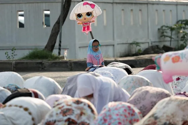 Muslim girl holds a balloon while attending mass prayers at the Sunda Kelapa port during Eid al-Fitr, marking the end of the holy fasting month of Ramadan, in Jakarta, Indonesia, May 2, 2022. (Photo by Willy Kurniawan/Reuters)