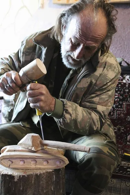 Abu Khalil, a 47-year-old Free Syrian Army fighter who is also a visual artist and decorator, carves a tank out of wood at Jabal al-Turkman in Latakia province January 20, 2015. (Photo by Alaa Khweled/Reuters)