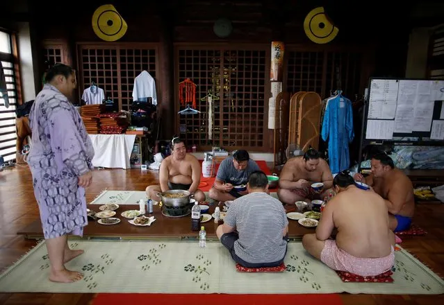 Mongolian-born Tomozuna Oyakata (3rd L), or master of the Tomozuna stable, and his wrestlers eat a meal inside the main hall of Ganjoji Yakushido temple in Nagoya, Japan on July 18, 2017. With rare permission granted by sumo's governing body, Reuters was able to observe the stable's wrestlers training at their temporary Buddhist temple base for the Nagoya Grand Sumo Tournament that kicked off last week, gaining insight into the intricacies of sumo. (Photo by Issei Kato/Reuters)