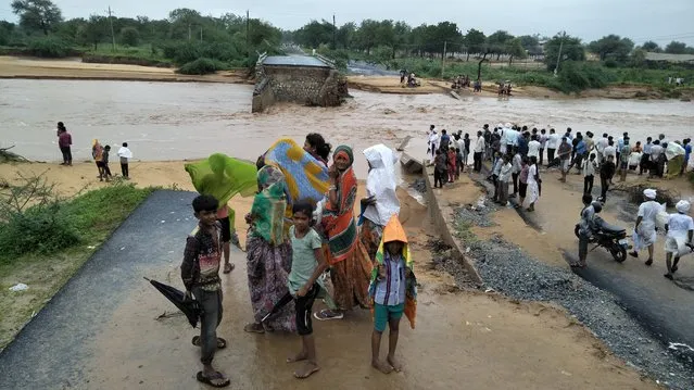 People watch after a small bridge on the Deesa Dhanera highway was washed away in monsoon floods in Gujarat state, India, Tuesday, July 25, 2017. The death toll in Gujarat has risen to 70 since the start of the monsoon season, which runs from June through September. (Photo by Prakash Patel/AP Photo)