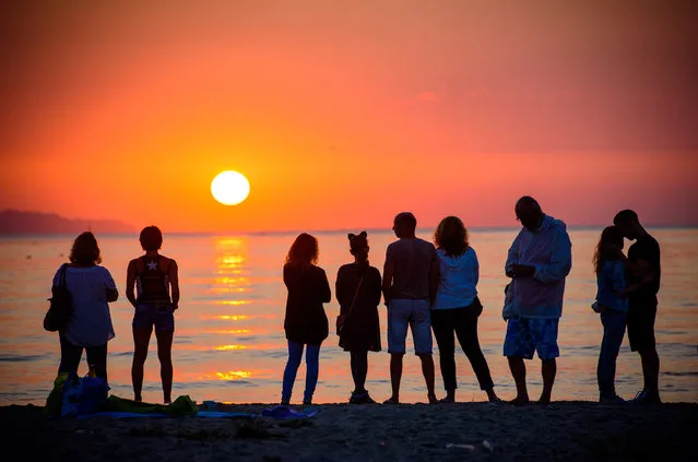 Bulgarians watch the sun rise on the shore of the Black Sea on July 1, 2016 in Varna, Bulgaria. (Photo by Rex Features/Shutterstock)
