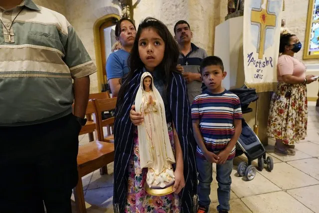 Paola Martinez stands with her family as she holds a Virgin Mary statute during a multi-faith memorial Mass and prayer vigil at San Fernando Cathedral to honor the victims and survivors of the recent human smuggling tragedy, Thursday, June 30, 2022, in San Antonio. More than 50 people died in Monday's human-smuggling attempt. (Photo by Eric Gay/AP Photo)