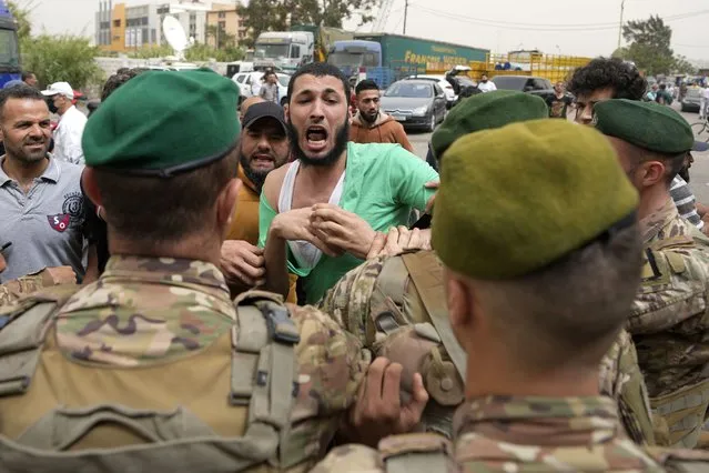 Lebanese army soldiers try to calm an angry relative of a man who is one of the missing migrants from an overnight sinking of a boat, outside the seaport, in Tripoli, north Lebanon, Sunday, April 24, 2022. The Lebanese military announced that 47 people were rescued and some bodies recovered from the migrant boat. Several survivors told local TV stations that the Lebanese navy ship rammed their migrant boat twice, damaging it. (Photo by Hassan Ammar/AP Photo)