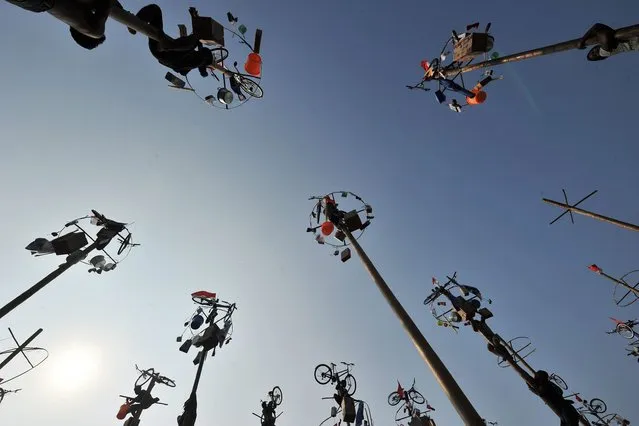 Flags and various prizes, including bicycles, sit at the top of poles before that start of a local competition called “panjat pinang” in which people try to climb greased poles to get the prizes, during an event to celebrate Indonesia's Independence Day in Jakarta on August 17, 2014. (Photo by Adek Berry/AFP Photo)