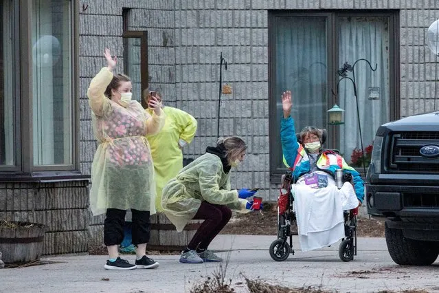 Workers and a resident wave at passing cars honking their horns in support for Pinecrest Nursing Home after several residents died and dozens of staff were sickened by coronavirus disease (COVID-19) in Bobcaygeon, Ontario, Canada on March 30, 2020. (Photo by Carlos Osorio/Reuters)