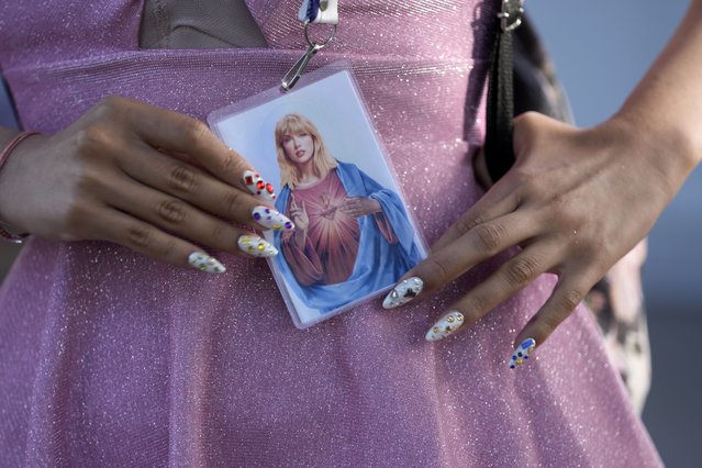 A fan holds a prayer-like card simulating Taylor Swift as the Most Sacred Heart of Jesus, before the start of The Eras Tour concert at the Monumental stadium in Buenos Aires, Argentina, Thursday, November 9, 2023. (Photo by Natacha Pisarenko/AP Photo)