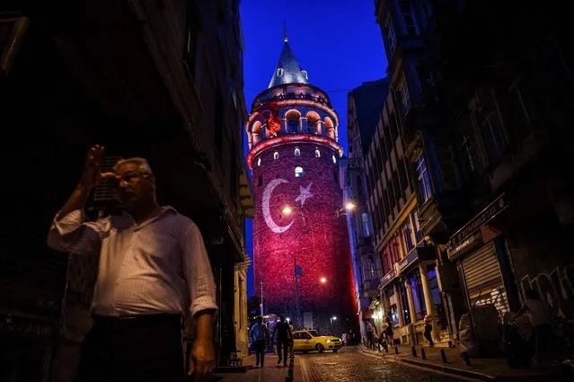 A man walks on a street near the Galata Tower, illuminated in Turkish flag colors on August 1, 2016 at Galata district in Istanbul. Turkey has arrested 11 fugitive soldiers suspected of involvement in an attack on President Recep Tayyip Erdogan's hotel during the night of the failed coup, the deputy prime minister said on August 1, 2016. (Photo by Ozan Kose/AFP Photo)