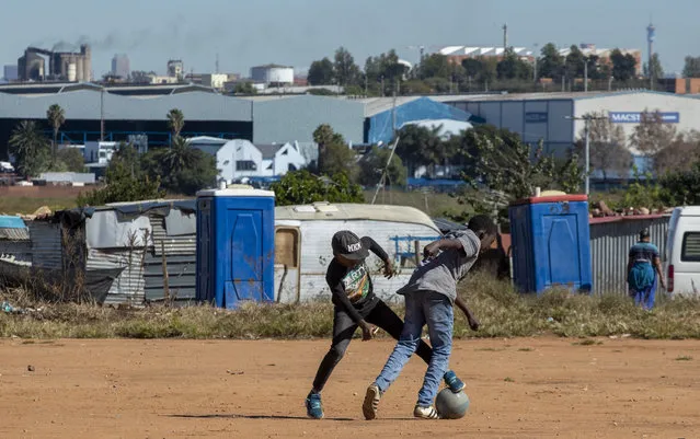 Young boys play soccer on a dusty field at Ramaphosa informal settlement, east of Johannesburg, South Africa, Tuesday, April 28, 2020. South Africa will begin a phased easing of its strict lockdown measures on May 1, although confirmed cases of coronavirus continue to increase. (Photo by Themba Hadebe/AP Photo)