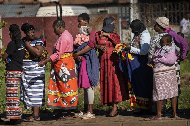 Women carrying their children lineup to receive vegetables from the Jan Hofmeyer community services in the Vrededorp neighborhood of Johannesburg Thursday, April 30, 2020. South Africa will began a phased easing of its strict lockdown measures on May 1, although its confirmed cases of coronavirus continue to increase. (Photo by Jerome Delay/AP Photo)