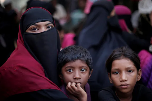 A Rohingya refugee family sits in a queue as they wait to receive humanitarian aid at Kutupalong refugee camp near Cox's Bazar, Bangladesh October 24, 2017. (Photo by Adnan Abidi/Reuters)