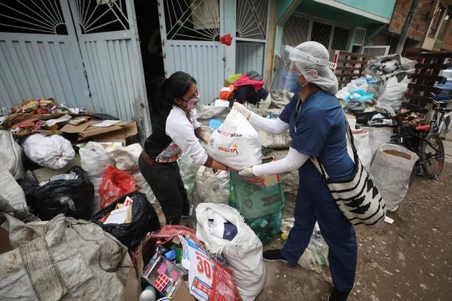 A City Hall worker delivers a bagful of free food to a resident amid a lockdown to help curb the spread of the new coronavirus in Bogota, Colombia, Wednesday, May 27, 2020. The city government is distributing food to poor people who can't go out to work due to the lockdown. (Photo by Fernando Vergara/AP Photo)