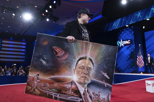 Elon Musk holds a painting after speaking at the Conservative Political Action Conference, CPAC, at the Gaylord National Resort & Convention Center, Thursday, February 20, 2025, in Oxon Hill, Md. (Photo by Jose Luis Magana/AP Photo)