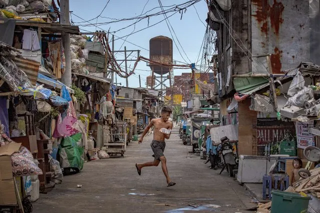 A resident who bought a tube of ice runs across an empty alley to avoid being caught by police for violating stay at home orders at a slum community as government imposes lockdown measures to curb the spread of the coronavirus on May 4, 2020 in Manila, Philippines. Parts of the Philippines, including the capital Manila, remain on lockdown as authorities continue to struggle with the growing number of COVID-19 cases. Land, sea, and air travels have been suspended, while government work, schools, businesses, and public transportation have been ordered to shutdown in a bid to keep some 55 million people at home. The Philippines' Department of Health has so far confirmed 9,223 cases of the coronavirus in the country, with at least 607 recorded fatalities. (Photo by Ezra Acayan/Getty Images)