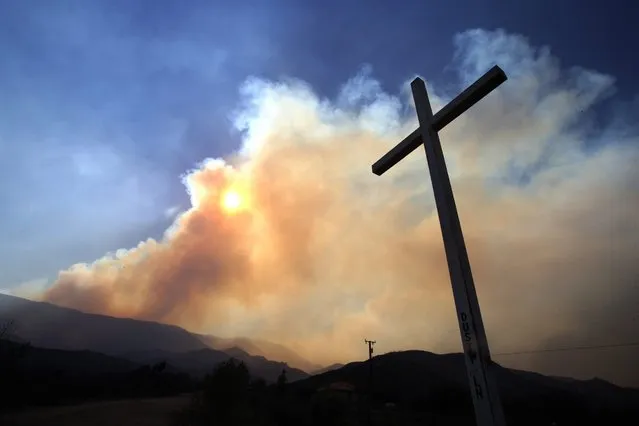Smoke rises from the Blue Cut Fire near Phelan, California, USA, 17 August 2016. The Blue Cut Fire, located some 80 miles (around 126km) from Los Angeles, has burned over 30,000 acres destroying dozens of homes, forcing the evacuation of over 80,000 people in the San Bernardino County. (Photo by Mike Nelson/EPA)