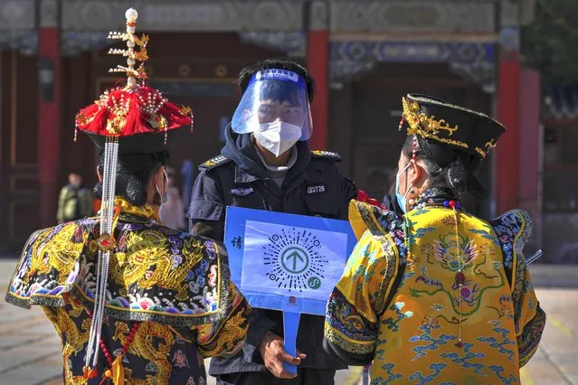 A security guard wearing a face shield and mask asks visitors wearing the emperor and empress costumes to scan their traveling code before entering to the Forbidden City during the opening ceremony of the 20th National Congress of China's ruling Communist Party in Beijing, China on Sunday, October 16, 2022. (Photo by Andy Wong/AP Photo)