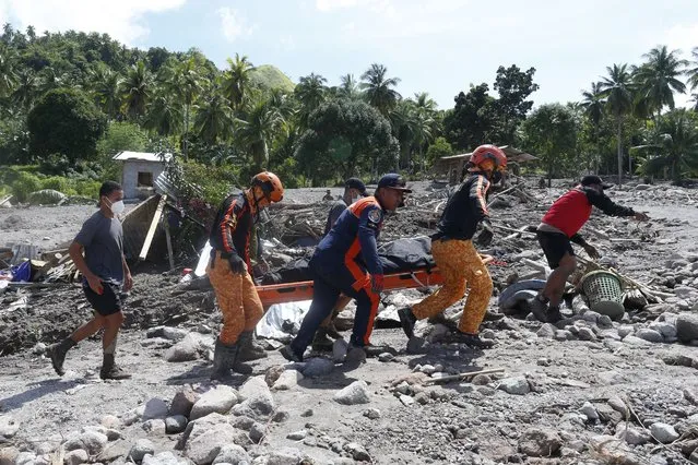 Rescuers carry a body at Maguindanao's Datu Odin Sinsuat town, southern Philippines on Sunday October 30, 2022. Victims of a huge mudslide set off by Tropical Storm Nalgae in a coastal Philippine village that had once been devastated by a killer tsunami mistakenly thought a tidal wave was coming and ran to higher ground toward a mountain and were buried alive, an official said Sunday. (Photo by AP Photo/Stringer)