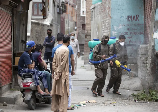 Kashmiri civic employees disinfect a residential area after a woman tested positive for COVID-19 in Srinagar, Indian controlled Kashmir, Monday, July 13, 2020. Authorities reimposed lockdown on Monday in parts of Indian-controlled Kashmir, including the region's main city, following surge in coronavirus cases. (Photo by Mukhtar Khan/AP Photo)