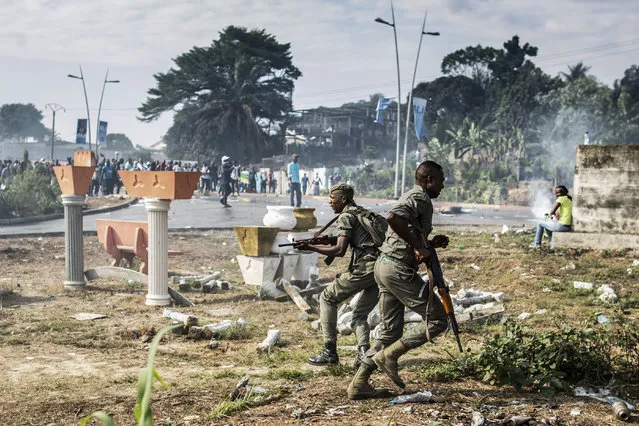 Gabonese soldiers run to take position as supporters of opposition leader Jean Ping protest in front of security forces blocking a demonstration trying to reach the electoral commission in Libreville on August 31, 2016. Bongo won by a narrow 5,594 votes of a total 627,805 registered voters. Turnout was 59.46 percent nationwide but soared to 99.93 percent in one of the country's nine provinces – the Haut-Ogooue, heartland of Bongo's Teke ethnic group – in a result hotly contested by the opposition. (Photo by Marco Longari/AFP Photo)