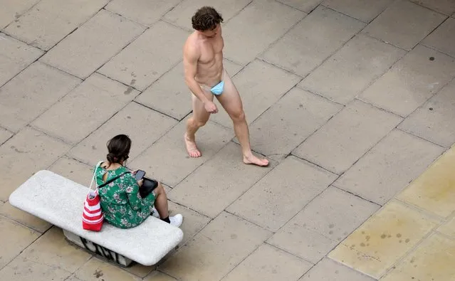 A man wearing a surgical mask as G-string walks past a woman, as the spread of the coronavirus disease (COVID-19) continues, on Oxford Street in London, Britain on July 24, 2020. (Photo by Simon Dawson/Reuters)