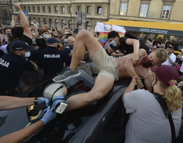 An activist climbs onto a police car to protest the detention of an LGBT activist in Warsaw, Poland, Friday, August 7, 2020. The incident comes amid rising tensions in Poland between LGBT activists and a conservative government that is opposed to LGBT rights. (Photo by Czarek Sokolowski/AP Photo)
