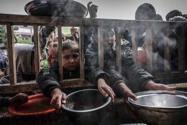 Displaced Palestinian children gather to receive food at a government school in Rafah in the southern Gaza Strip on February 19, 2024, amid the ongoing battles between Israel and the militant group Hamas. The UN children's agency UNICEF has warned that the alarming lack of food, surging malnutrition and disease could lead to an “explosion” in child deaths in Gaza. One in six children aged under two in Gaza was acutely malnourished, it estimated on February 19. (Photo by Mohammed Abed/AFP Photo)