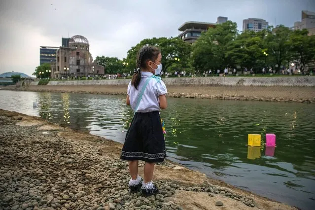 A little girl looks on as lanterns float on the river next to the Atomic Bomb Dome during a ceremony to mark the 75th anniversary of the Hiroshima atomic bombing that has been scaled back significantly because of concerns over coronavirus, on August 6, 2020 in Hiroshima, Japan. In a ceremony that has been scaled back significantly because of Covid-19 coronavirus, Japan will mark the 75th anniversary of the first atomic bomb that was dropped by the United States on Hiroshima on August 6, 1945. The bomb instantly killed an estimated 70,000 people and thousands more in coming years from radiation effects. Three days later the United States dropped a second atomic bomb on Nagasaki which ended World War II. (Photo by Carl Court/Getty Images)