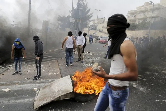 A masked Palestinian holds stones during clashes with Israeli police in Sur Baher, a village in the suburbs of Arab east Jerusalem, October 7, 2015. (Photo by Ammar Awad/Reuters)