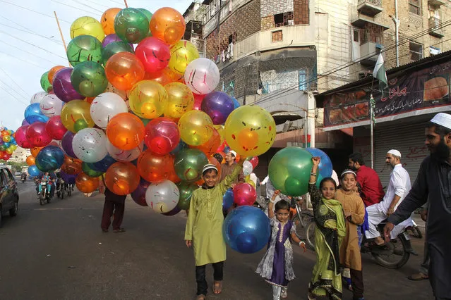 Pakistani children buy balloons to celebrate the Eid al Adha in Karachi, Pakistan, Tuesday, September 13, 2016. Pakistani Muslims are celebrating the Eid al-Adha, or the Feast of the Sacrifice, on Tuesday to mark the willingness of the Prophet Ibrahim – Abraham to Christians and Jews – to sacrifice his son. During the holiday Muslims slaughter sheep and cattle, distribute part of the meat to the poor and eat the rest. (Photo by Fareed Khan/AP Photo)