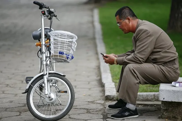 A man uses his mobile phone next to an electric bicycle in downtown Pyongyang, North Korea October 8, 2015. (Photo by Damir Sagolj/Reuters)