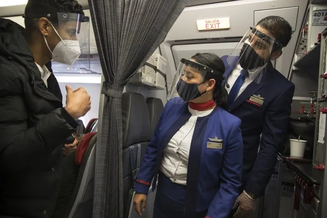 Flight attendants from the LAN company using protective gear due to the COVID-19, listen to a passenger minutes before a flight take off from Lima to Pucallpa, Peru, Saturday, August 29, 2020. (Photo by Rodrigo Abd/AP Photo)
