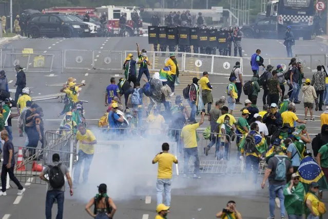Protesters, supporters of former President Jair Bolsonaro, clash with police during a protest outside the Planalto Palace building in Brasilia, Brazil, Sunday, January 8, 2023. Others demonstrators stormed congress and the Supreme Court. (Photo by Eraldo Peres/AP Photo)