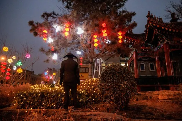 A worker looks at Spring Festival decorations ahead of Chinese Lunar New Year festivities in Beijing, China on January 12, 2023. (Photo by Thomas Peter/Reuters)