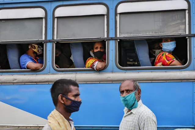 Commuters wearing face masks to prevent coronavirus wait inside a bus as pedestrians walk past at a bus terminus in Kolkata, India, Thursday, October 1, 2020. India is expected to become the pandemic's worst-hit country within weeks, surpassing the United States. (Photo by Bikas Das/AP Photo)
