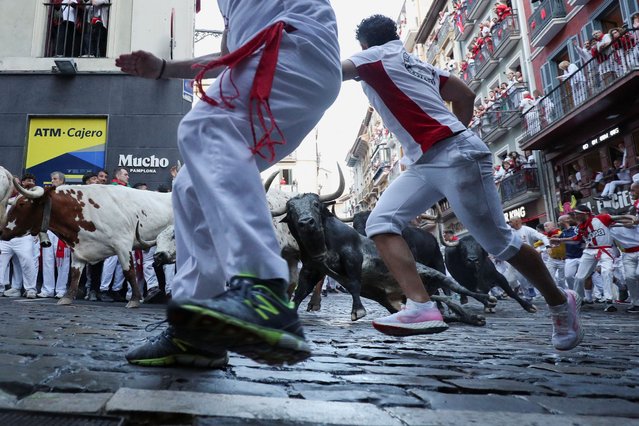 Revellers sprint next to a Cebada Gago fighting bulls during the Encierro (running of the bulls), at the Mercaderes corner, during the San Fermin festival in Pamplona, Spain, on July 8, 2025. (Photo by Albert Gea/Reuters)