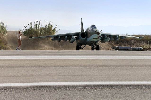A Russian ground staff member signals to the pilot of a Sukhoi Su-25 fighter jet at the Hmeymim air base near Latakia, Syria, in this handout photograph released by Russia's Defence Ministry on October 22, 2015. (Photo by Reuters/Ministry of Defence of the Russian Federation)