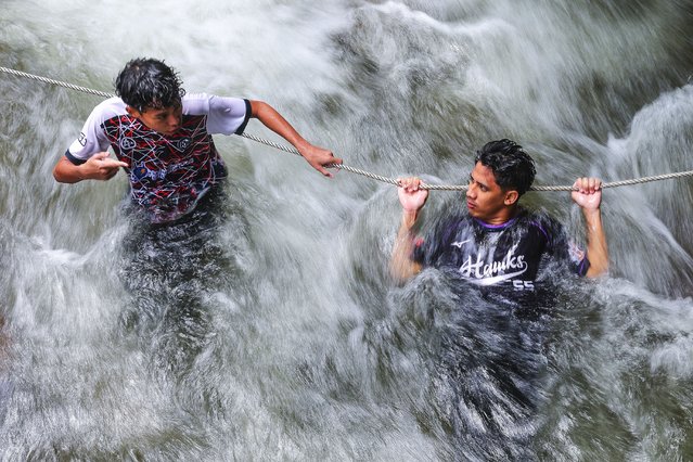 An image made with a slow shutter speed shows men holding onto a rope amid strong river currents while trying to cool off in Tanjung Malim, state of Perak, Malaysia, 03 June 2025. Earlier in May 2025, Malaysian Meteorological Department director-general Dr. Mohd Hisham Mohd Anip said, “The Southwest Monsoon is expected to begin on May 10 and continue until September. During the monsoon, lower humidity levels typically lead to reduced rain cloud formation across most areas. As a result, the country will experience reduced rainfall during this period, with more dry days than rainy ones”. (Photo by Fazry Ismail/EPA/EFE)