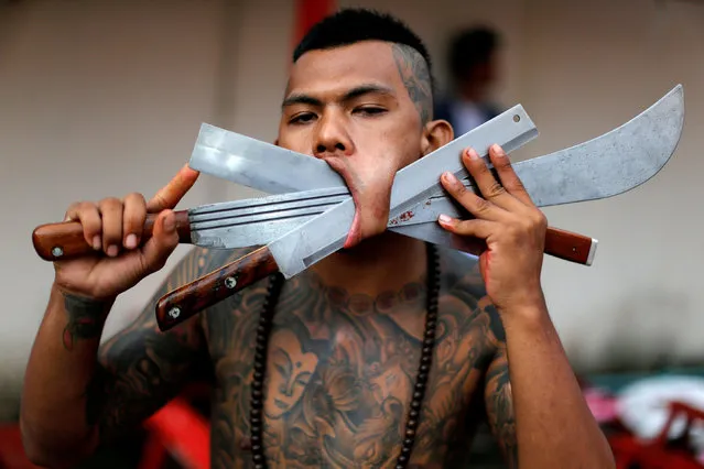 A devotee of the Chinese Bang Neow shrine poses with his cheek pierced with blades as he takes part in a procession celebrating the annual vegetarian festival in Phuket, Thailand October 6, 2016. (Photo by Jorge Silva/Reuters)