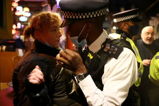 A police officer wearing a protective face mask speaks to a woman as pubs close ahead of the lockdown in Soho, London, Britain, November 4, 2020. (Photo by Henry Nicholls/Reuters)