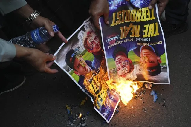 Muslim protesters burn posters during a rally outside the Swedish Embassy in Jakarta, Indonesia, Monday, January 30, 2023. Hundreds of Indonesian Muslims marched to the heavily guarded Swedish Embassy in the country's capital on Monday to denounce the recent desecration of Islam's holy book by far-right activists in Sweden and the Netherlands. (Photo by Tatan Syuflana/AP Photo)