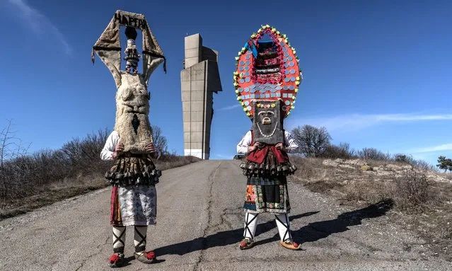 Performing “Mummers” Stoimen Petrov, 24 years-old, (L) and Ivan Nikolov, 24 years-old, (R) pose for a photograph in front the Bulgarian Soviet friendship monument ahead of the annual celebrations of the Masquerade Kukeri Games on February19, 2022 in Chargan, Bulgaria. The performances of the traditional masked dancers known as “kukeri” are believed to banish evil spirits as they parade through towns disguised as mythological characters. (Photo by Hristo Rusev/Getty Images)