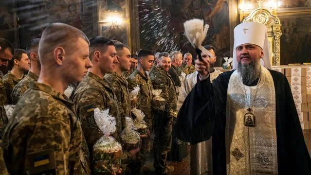 Metropolitan Epiphanius I, head of the Orthodox Church of Ukraine sprinkles holy water on Ukrainian servicemen with Easter cakes during a special service for Ukrainian Armed Forces, amid Russia's attack on Ukraine, during a ceremony to bless Easter cakes at St Michael’s Cathedral before Orthodox Christmas in Kyiv, Ukraine on April 12, 2023. (Photo by Vladyslav Musiienko/Reuters)