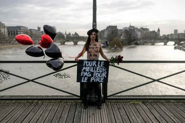 A member of the feminist movement Femen holds a banner reading “For the best not the worst” as she is chained on the pont des Arts in Paris on February 14, 2020 on Valentine's day during an action to denounce violence against women. (Photo by Lionel Bonaventure/AFP Photo)