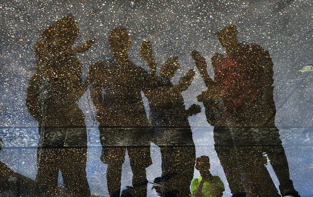 Pokemon Go players check in at the waterfront area near the Jefferson Memorial in Washington, D.C. on July 30, 2016. They are reflected in a puddle that resulted from a moderate rain that came through just before they began their march around town. Thousands of of Pokemon Go players converged on the Capitol today and competed as teams. Many of the hot spots for catching Pokemon's were near the various well known Washington monuments. (Photo by Michael S. Williamson/The Washington Post)