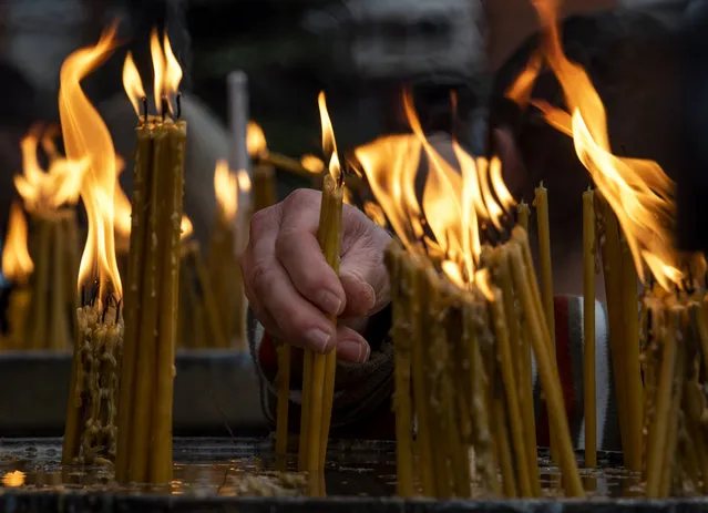 An Orthodox believer lights candles during a Christmas mass outside the central Orthodox Church of Saint Clement in Skopje, Republic of North Macedonia, 07 January 2021. Orthodox Christians celebrate Christmas Day on 07 January according to the Julian calendar. (Photo by Georgi Licovski/EPA/EFE)