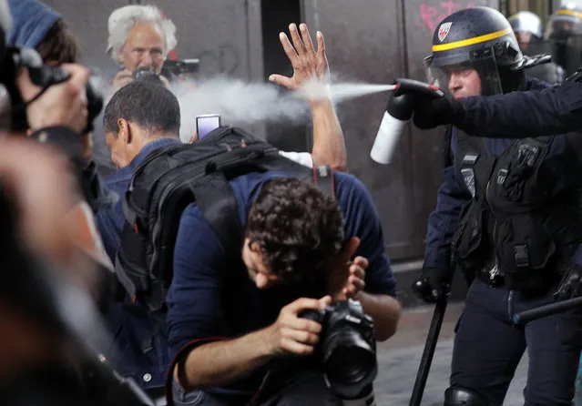 Riot police officers spray gas at photographers during scuffles part of a demonstration in Paris, Tuesday, May 22, 2018. French public services workers have gone on strike as part of their protest a government plan to cut 120,000 jobs by 2022. (Photo by Christophe Ena/AP Photo)