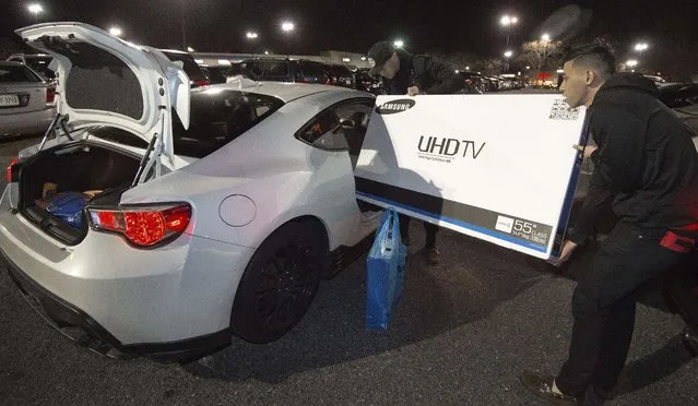 Two men try to load their just purchased Samsung 55" TV  into a car, at a Best Buy store  in Fairfax, Virginia on November 26, 2015, on a Black Friday sale that started a day earlier during Thanksgiving evening.   The  US holiday shopping season kicks off with "Black Friday" – the day after the Thanksgiving holiday – with a frenzy expected at stores around the country as retailers slash prices. (Photo by Paul J. Richards/AFP Photo)