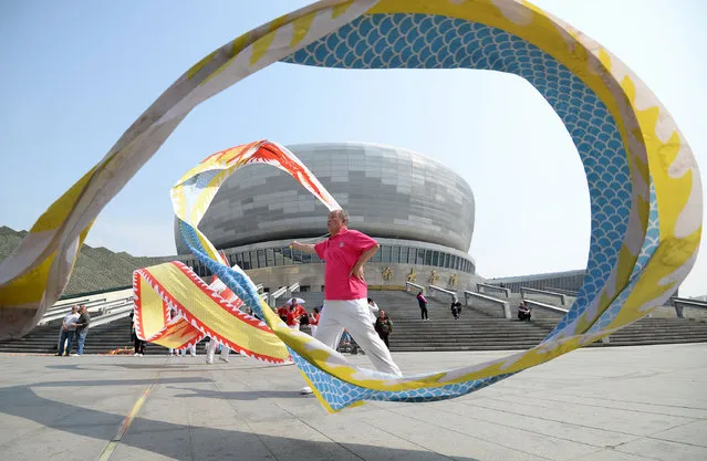 People display their skills with diabolos at Handan cultural and art centre square during the May Day holiday in Hebei, China on April 30, 2018. (Photo by Costfoto/Barcroft Images)