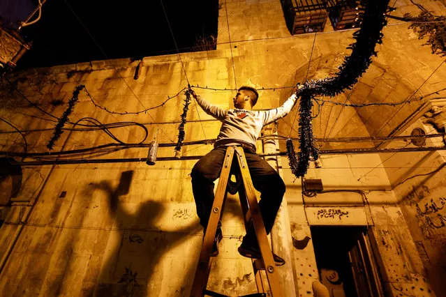 A man hangs decorations ahead of the holy month of Ramadan in Jerusalem's Old City, March 29, 2022. (Photo by Ammar Awad/Reuters)