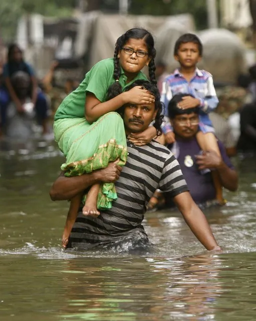 People carry children on their shoulders and wade through flood waters in Chennai, India, Thursday, December 3, 2015. (Photo by AP Photo)