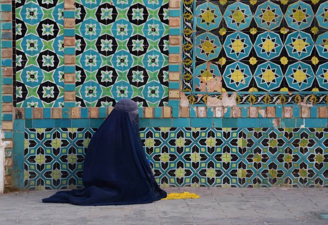 In this photo taken on May 23, 2018, an Afghan burqa-clad woman sits in the courtyard of Hazrat-e Ali shrine, or “Blue Mosque”, during the holy month of Ramadan in Mazar-i-Sharif. As well as abstinence and fasting during Ramadan, Muslims are encouraged to pray and read the Quran during Islam's holiest month. (Photo by Farshad Usyan/AFP Photo)